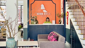 A reception area with a blue and orange wall, a wooden staircase, and a grey sofa. - Windbell Villa (Da Nang)