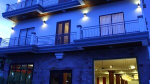 A multi-story hotel with balconies, a swimming pool, and a well-lit entrance. - Heart Language Angkor Hotel - Hostel (Siem Reap)
