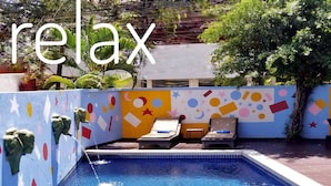 A swimming pool with geometric wall designs and lounge chairs. - Heart Language Angkor Hotel - Hostel (Siem Reap)