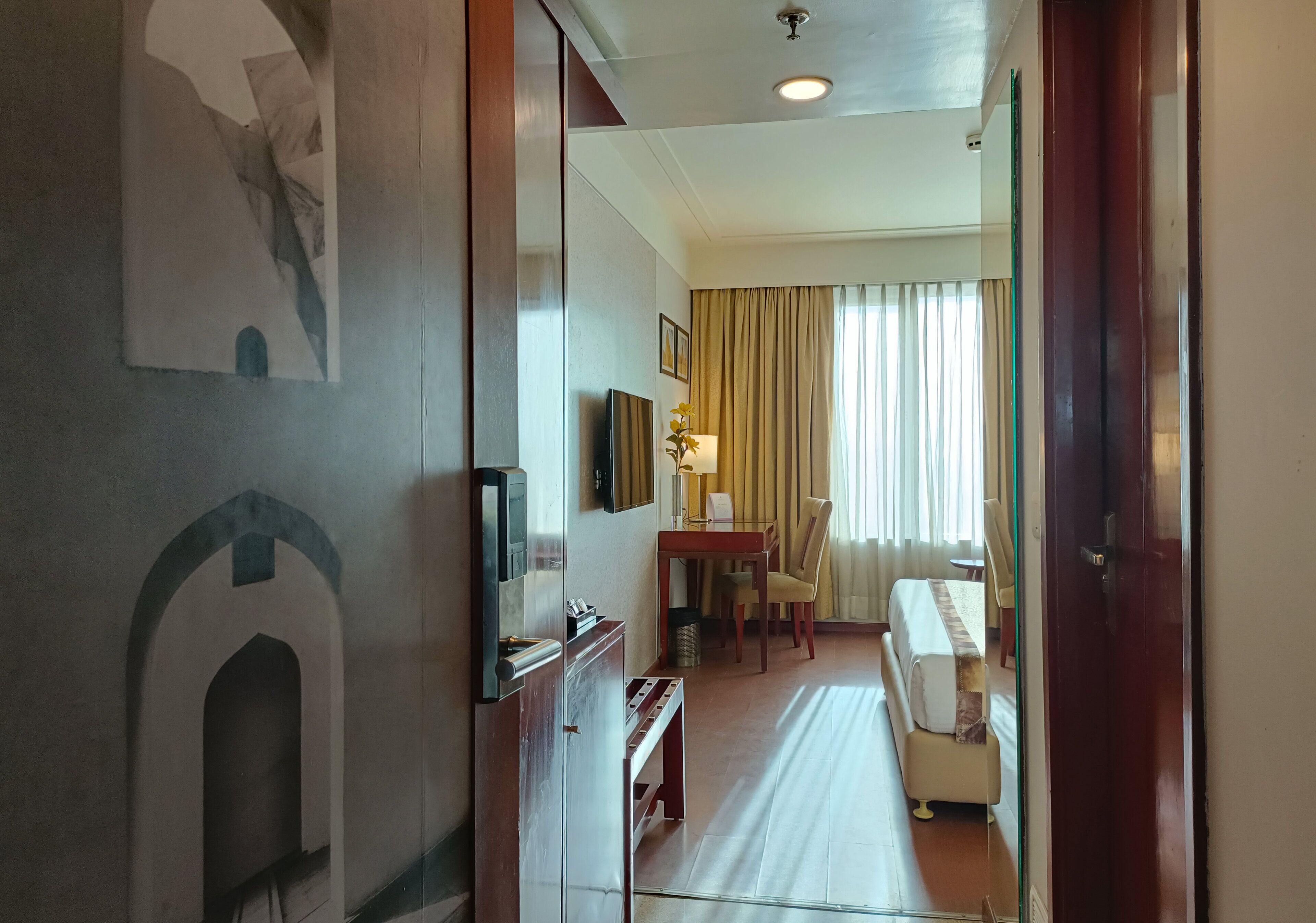Een hotelkamer met een bed, een bureau, een stoel, een televisie en een lamp.
