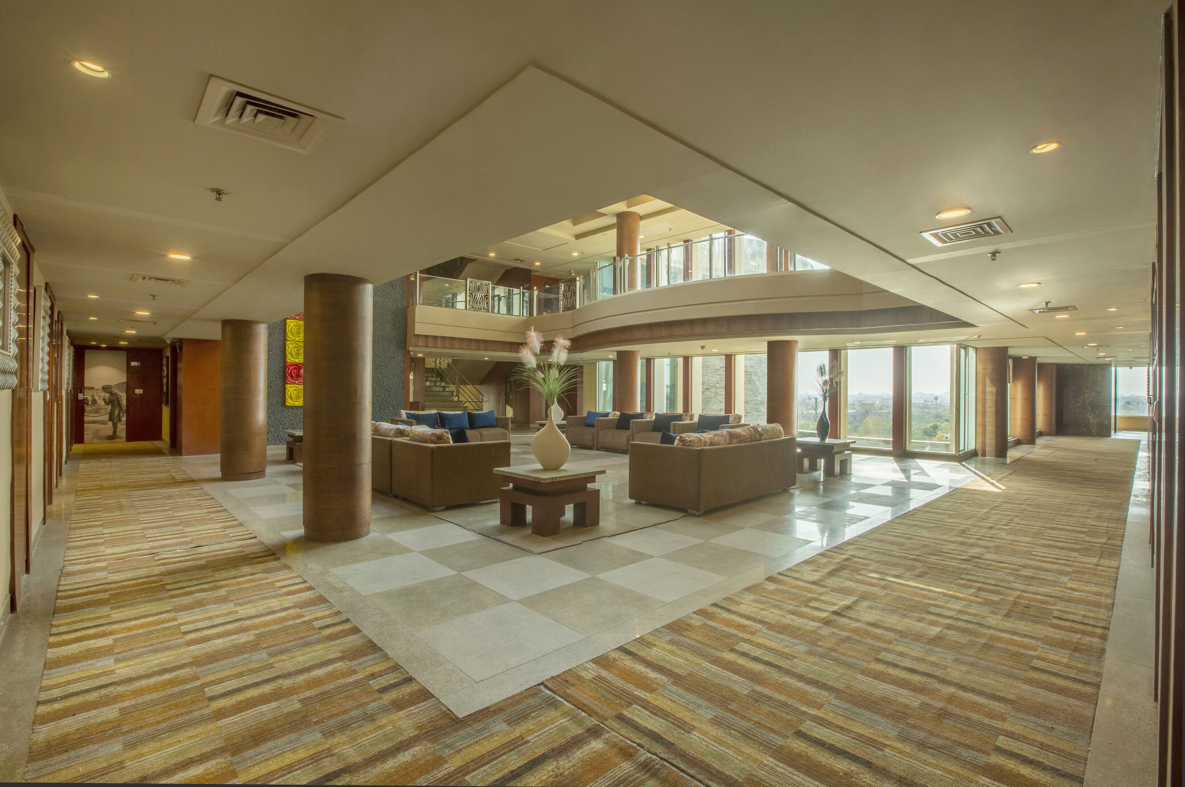 Eine geräumige Lobby mit Schachbrettmuster-Boden, mehreren Sitzbereichen und Blick ins Freie.