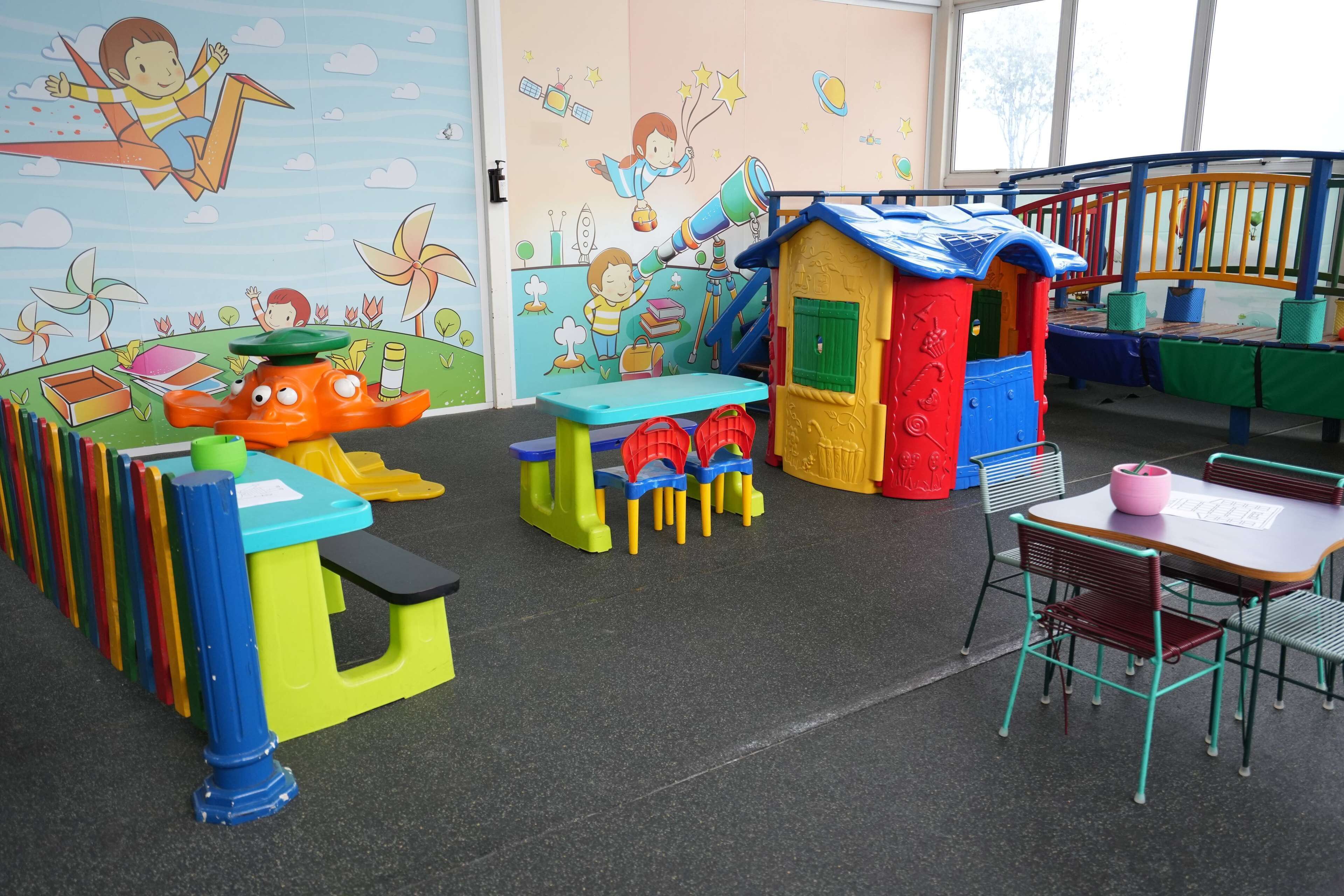 Zona de jocs infantil amb mobles i murals de colors.