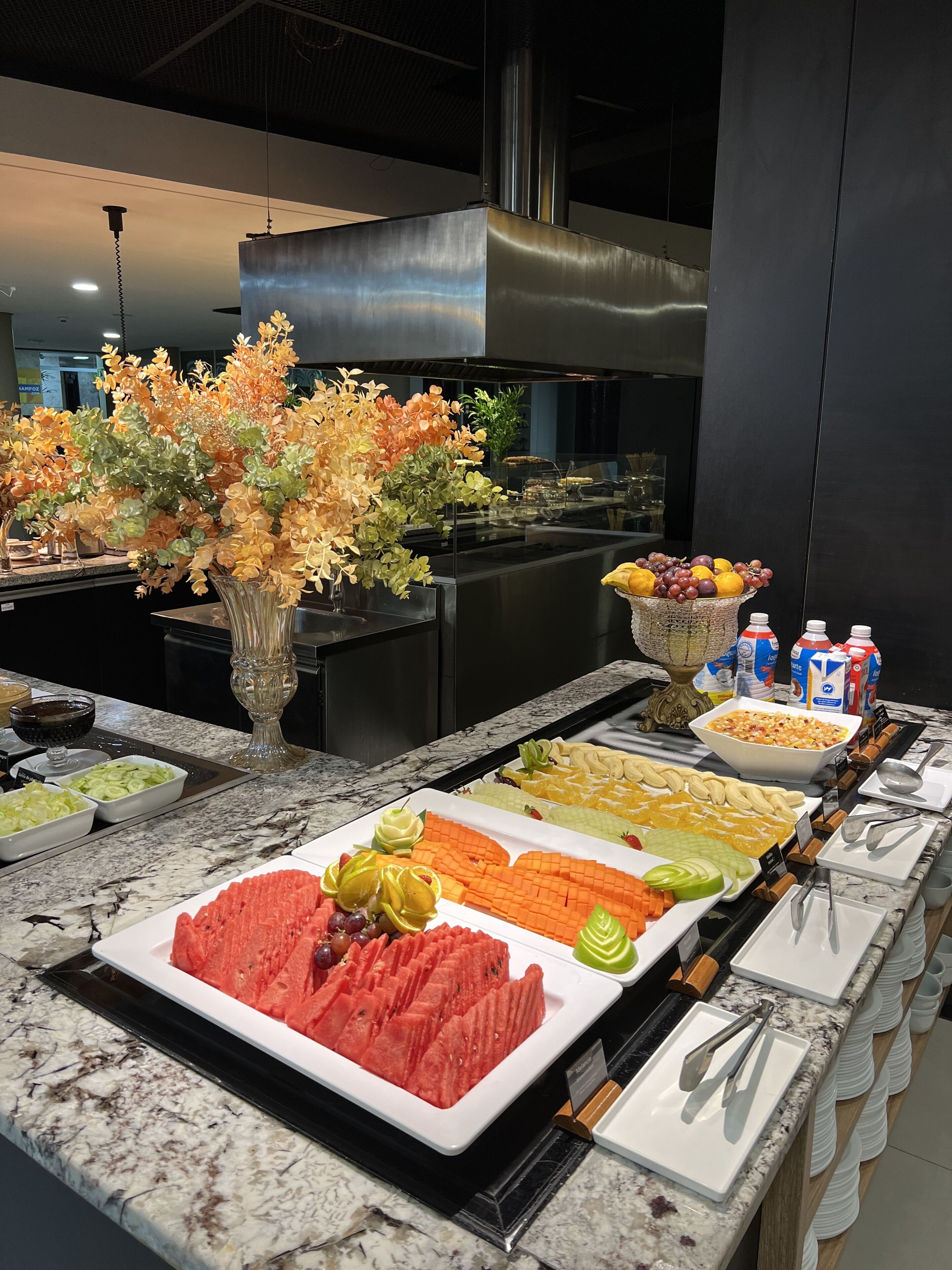 Un bufé con diferentes opciones de comida y un arreglo floral decorativo.