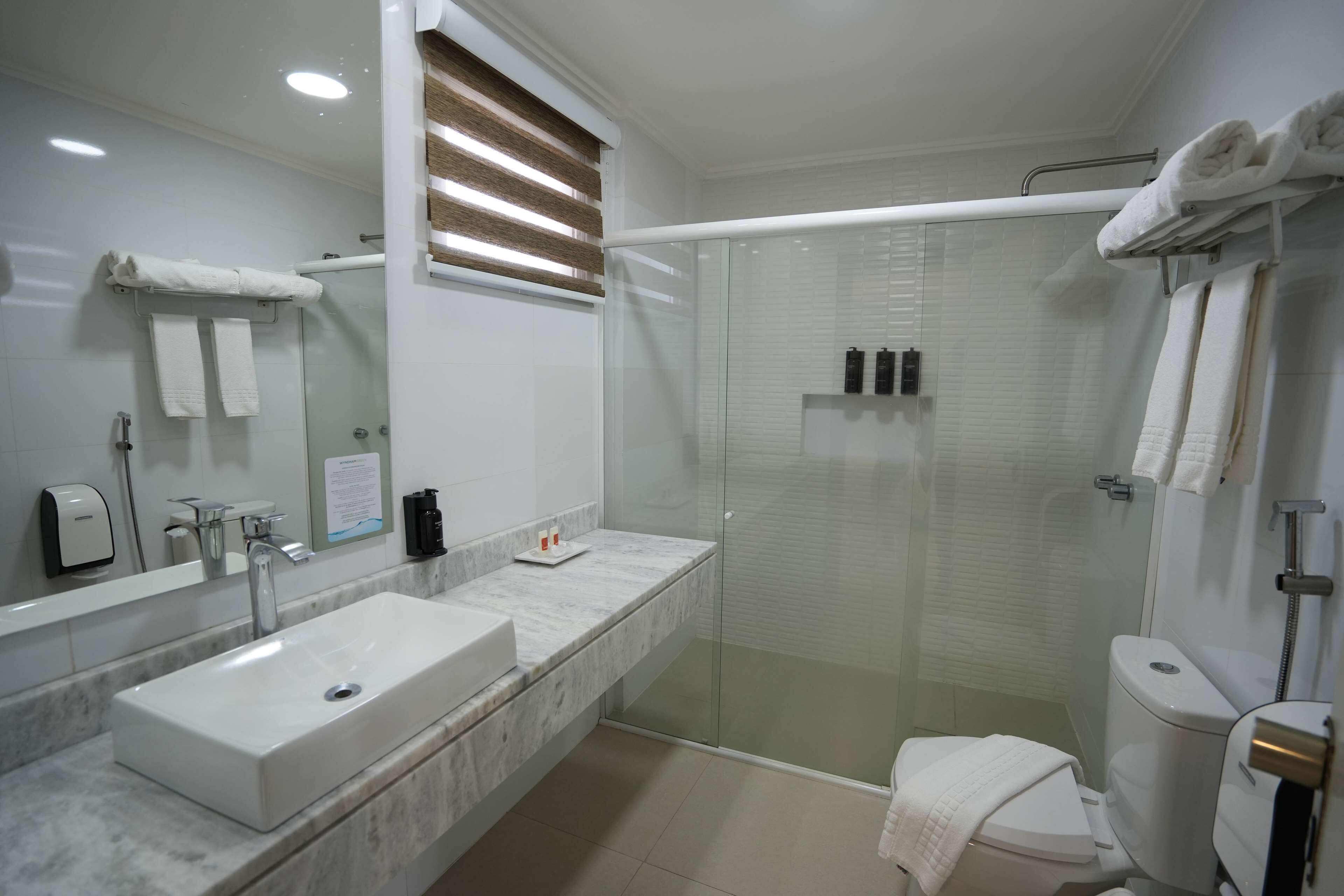 Un baño moderno con ducha acristalada, lavamanos de mármol y retrete.