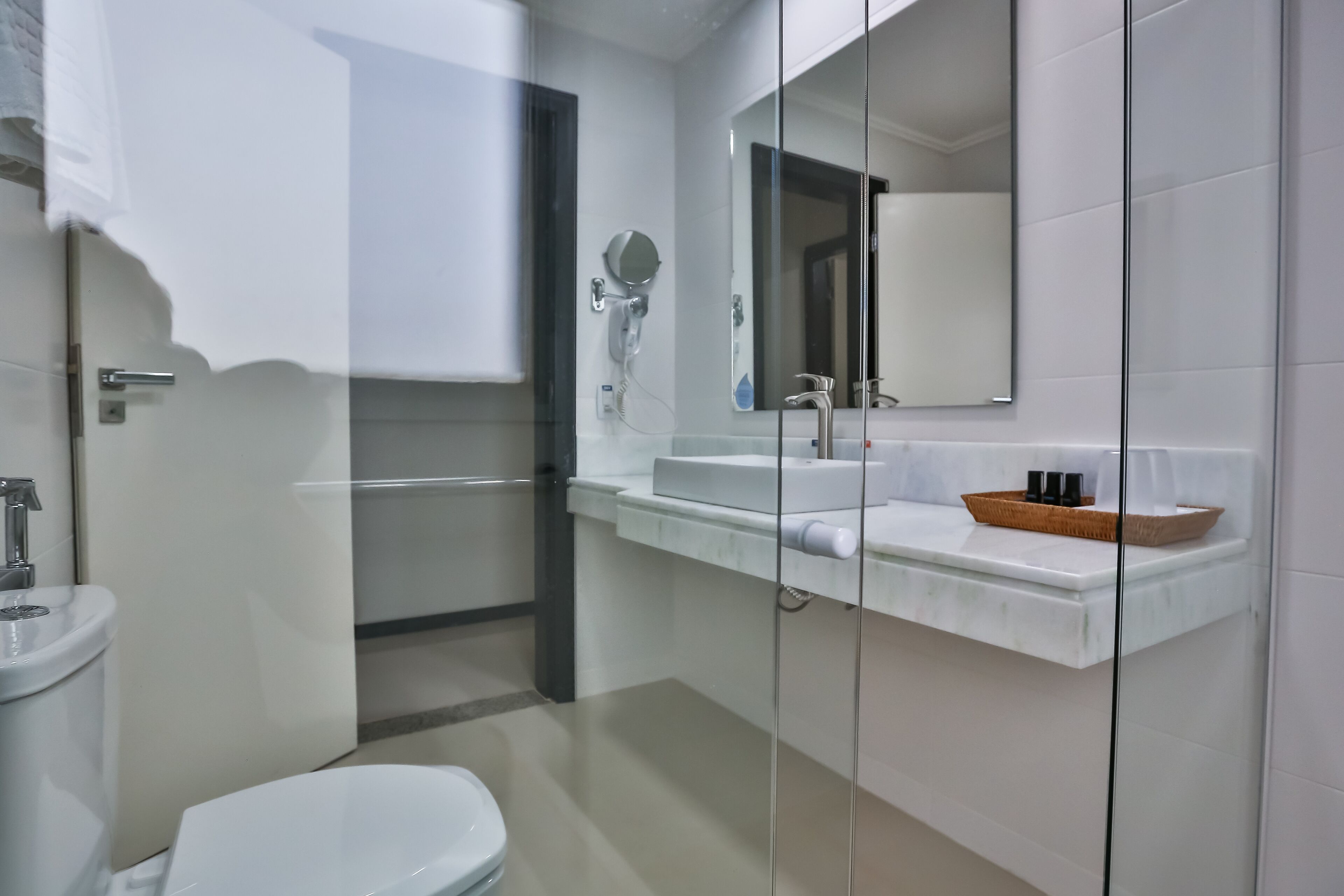 Un baño moderno con inodoro, lavamanos y cabina de ducha de vidrio.