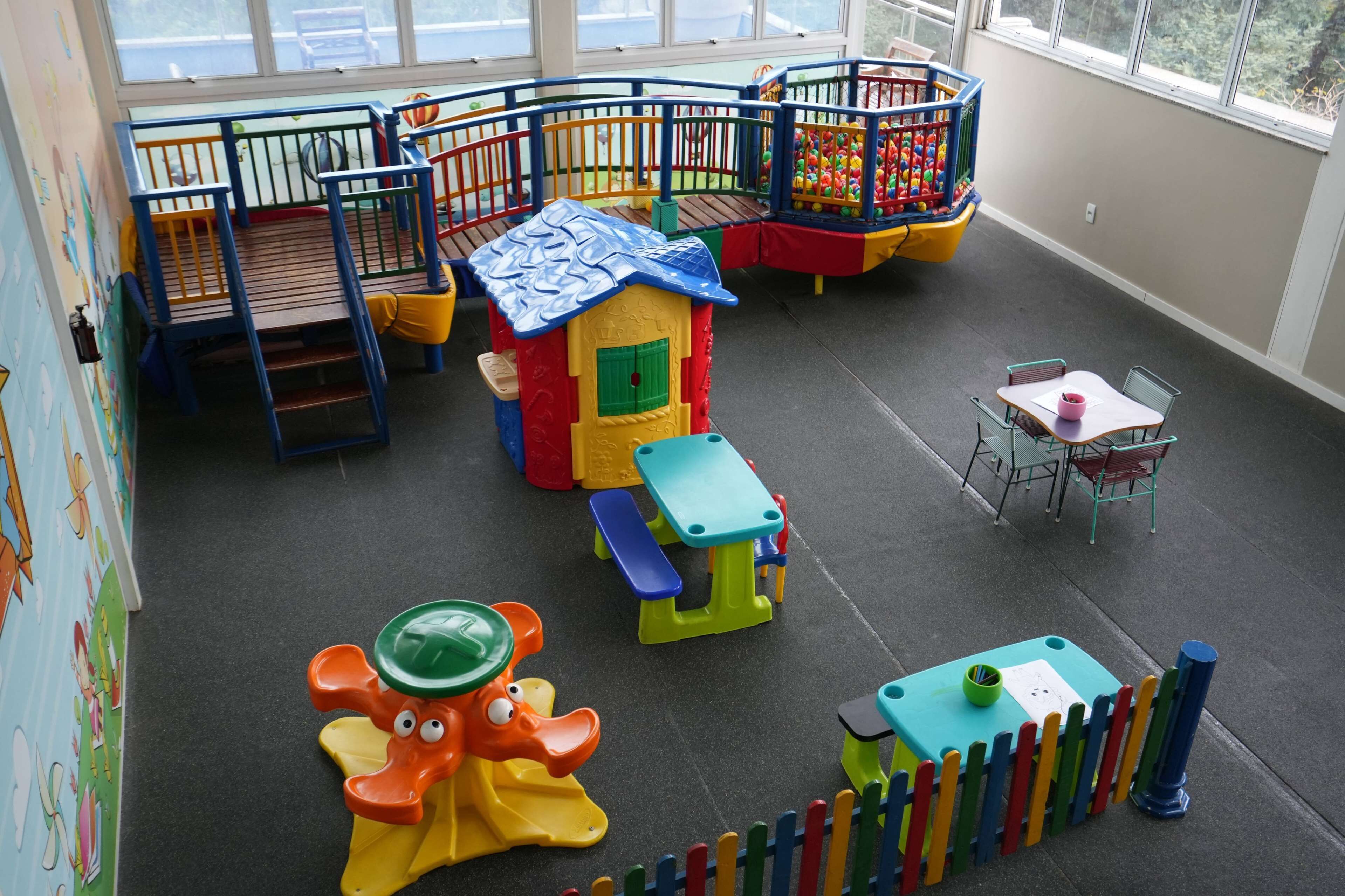 A children's play area with a small house, climbing structures, and a table with chairs.