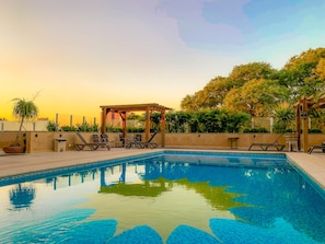 Una piscina al aire libre, tumbonas
