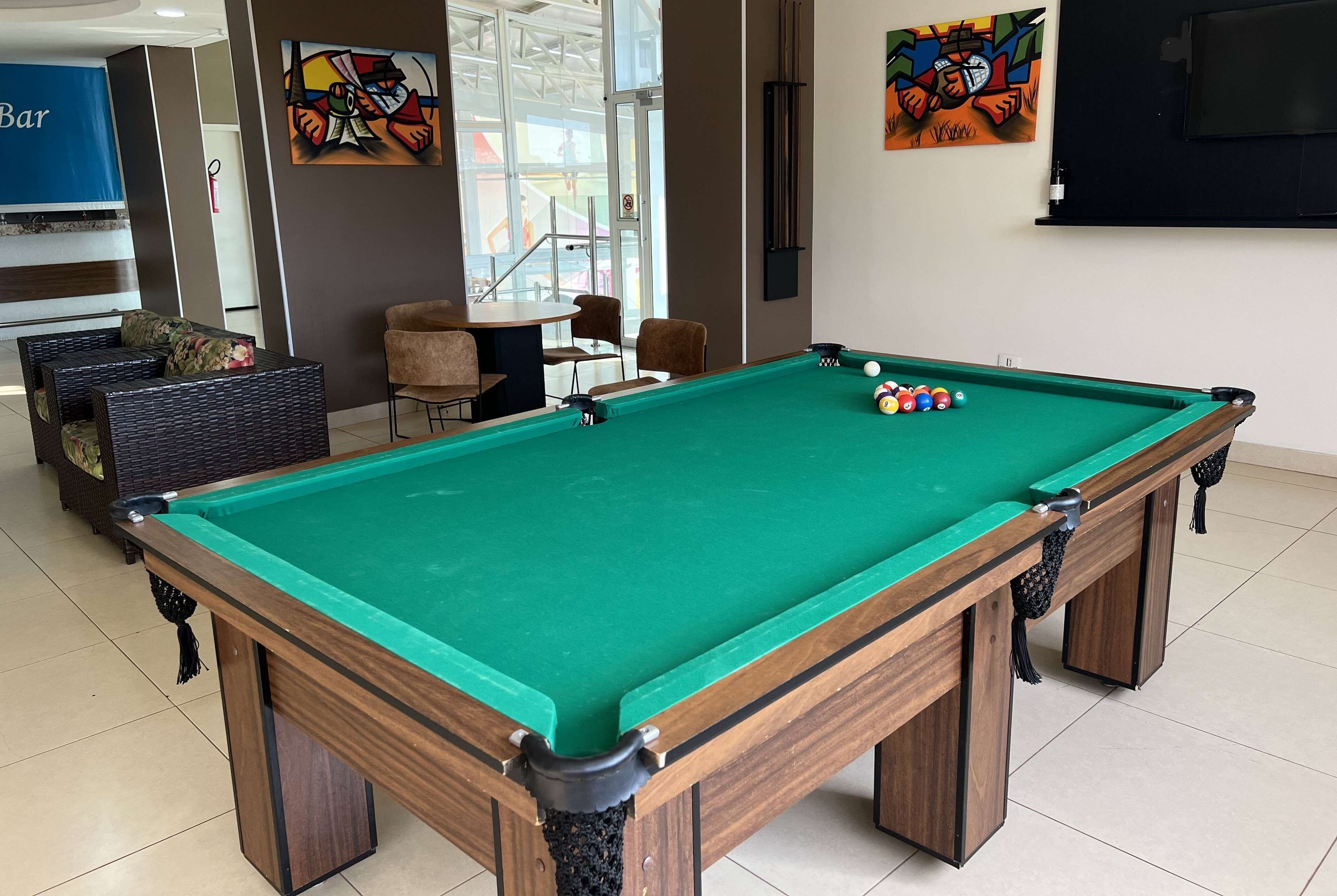 A pool table with a green felt surface, surrounded by chairs and a sofa.