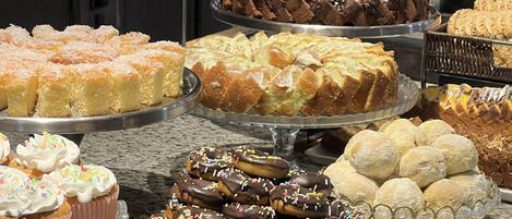 Un bufé con diversos postres, entre ellos pasteles, galletas y productos de pastelería.