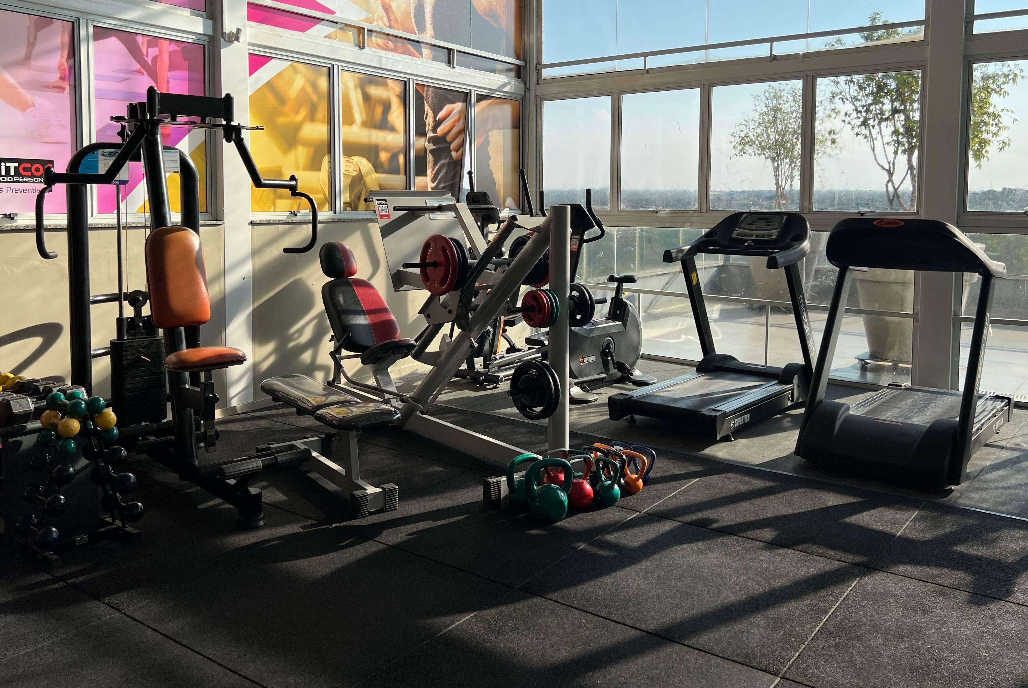 A gym with exercise equipment, treadmills, and kettlebells.