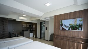 Ett hotellrum med en säng, ett skrivbord, en mikrovågsugn och en tv på väggen.