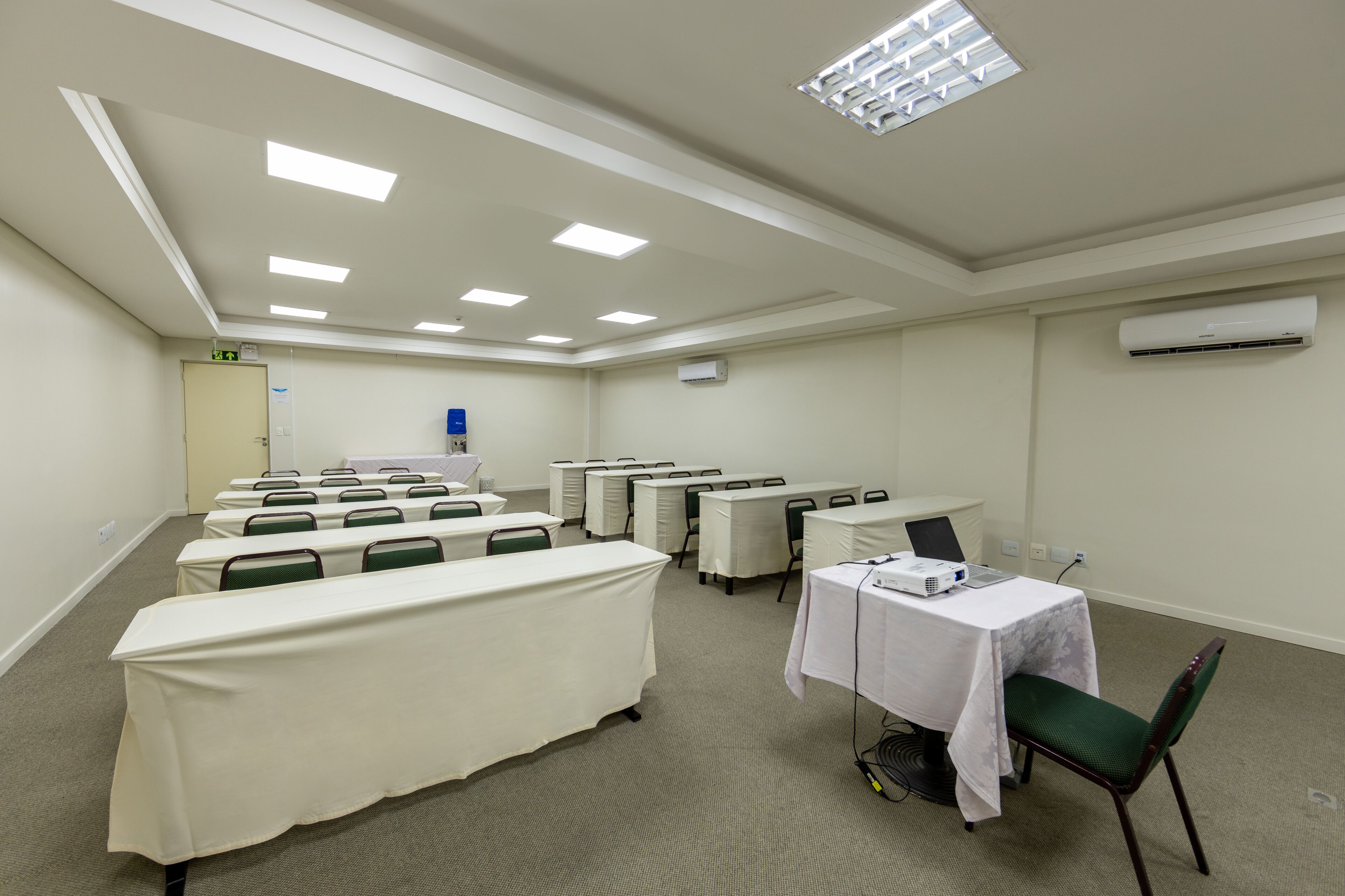 A conference room with multiple tables, chairs, and a projector on one table.