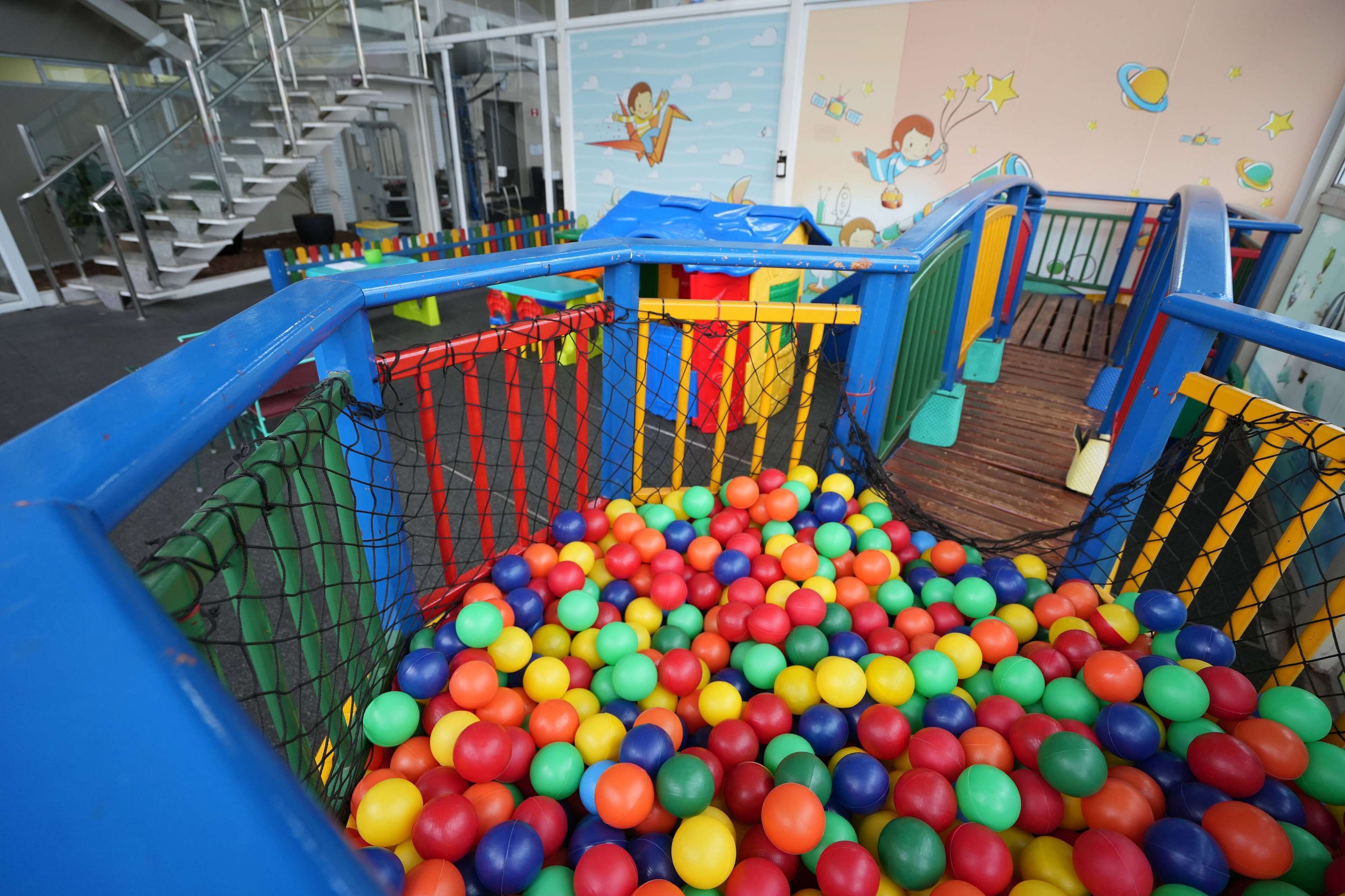 A play area with a ball pit and a slide, surrounded by a safety net.