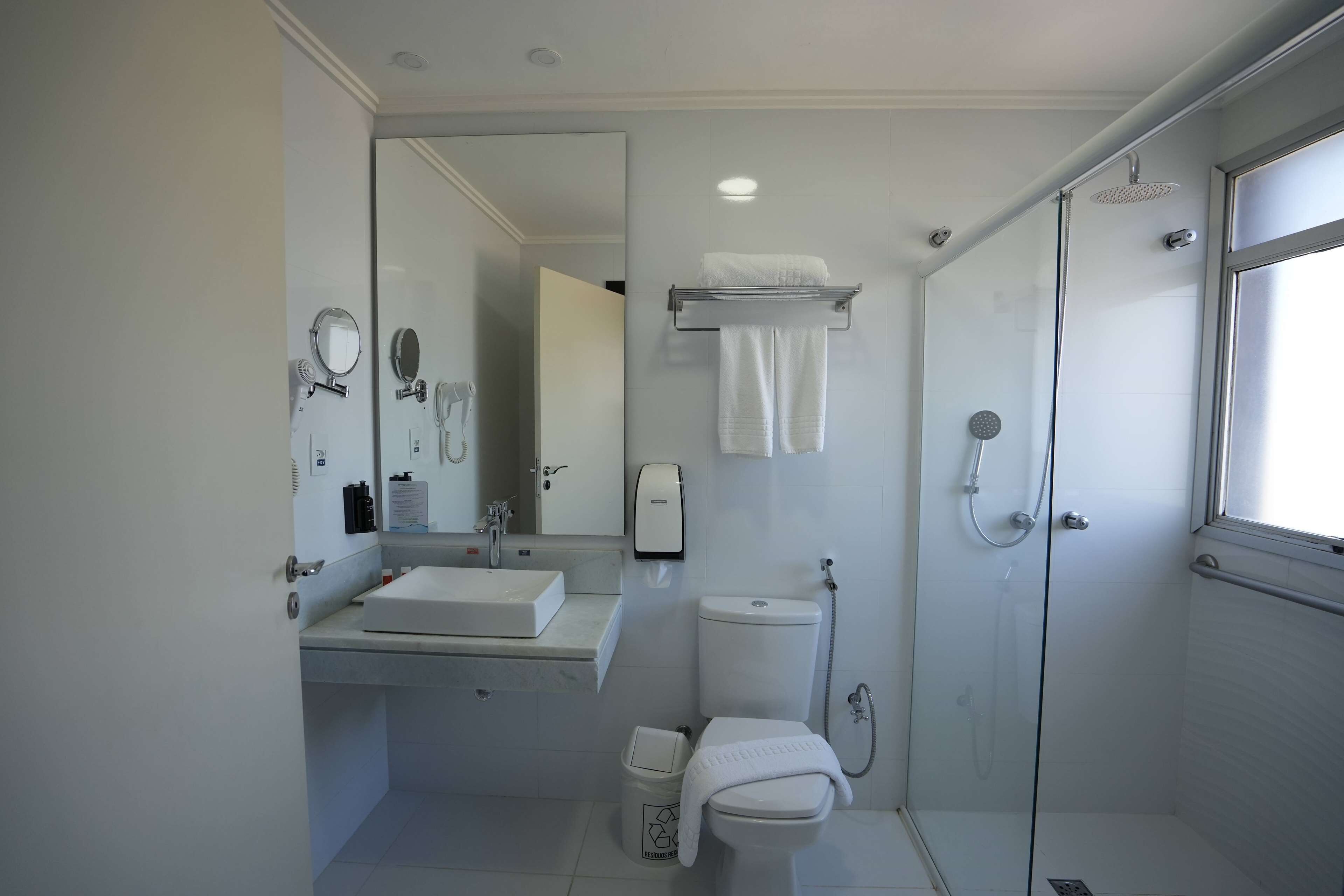 A modern bathroom with a glass-enclosed shower, a white sink, and a toilet.