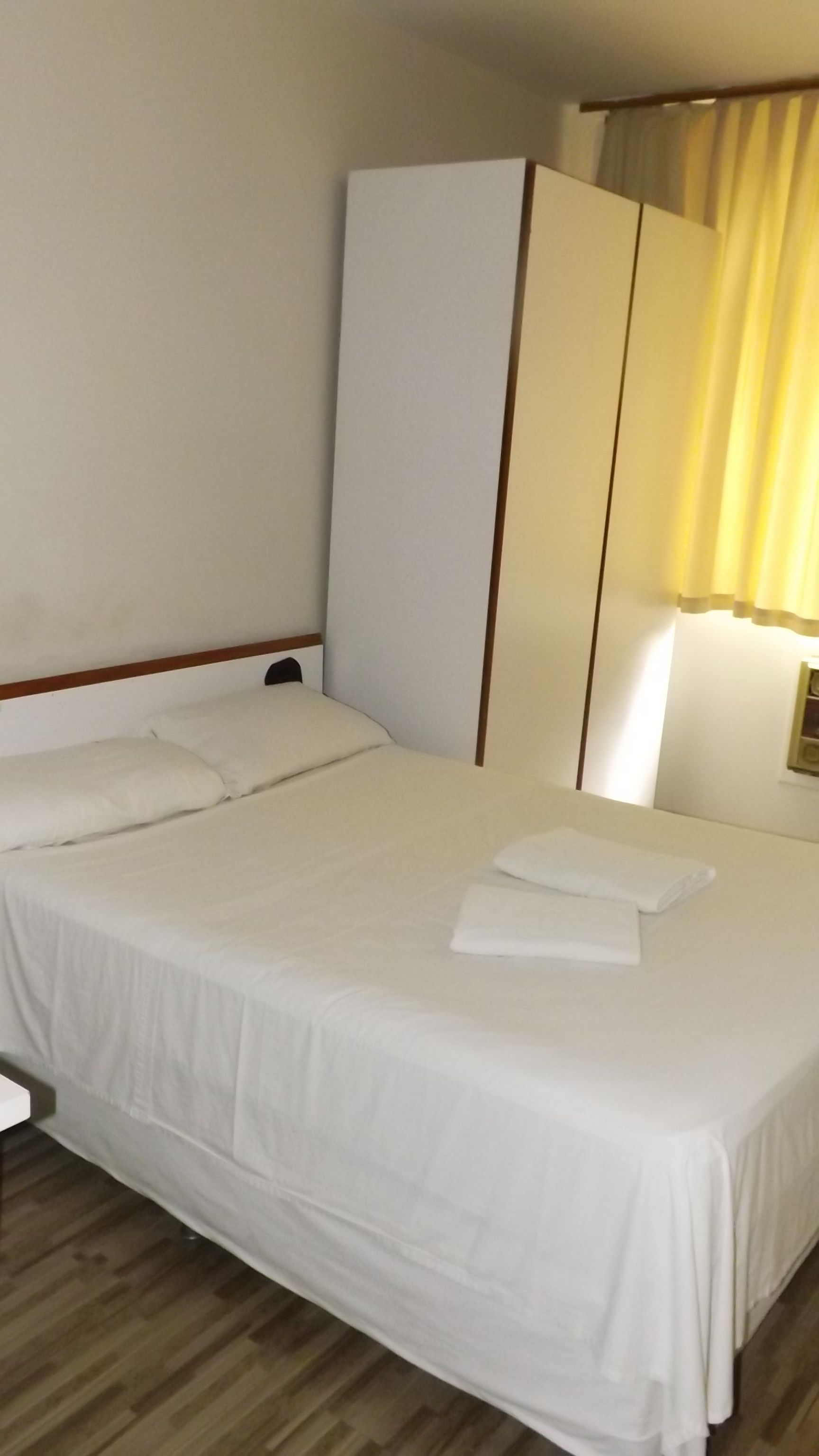 Siististi pedattu sänky valkoisilla lakanoiden kanssa hotellihuoneessa.