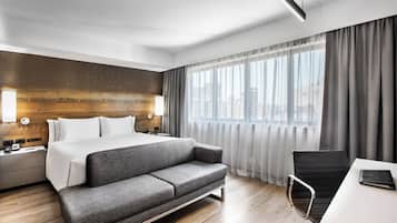 Habitació d'hotel moderna amb un llit gran, un sofà, escriptori i una cadira.