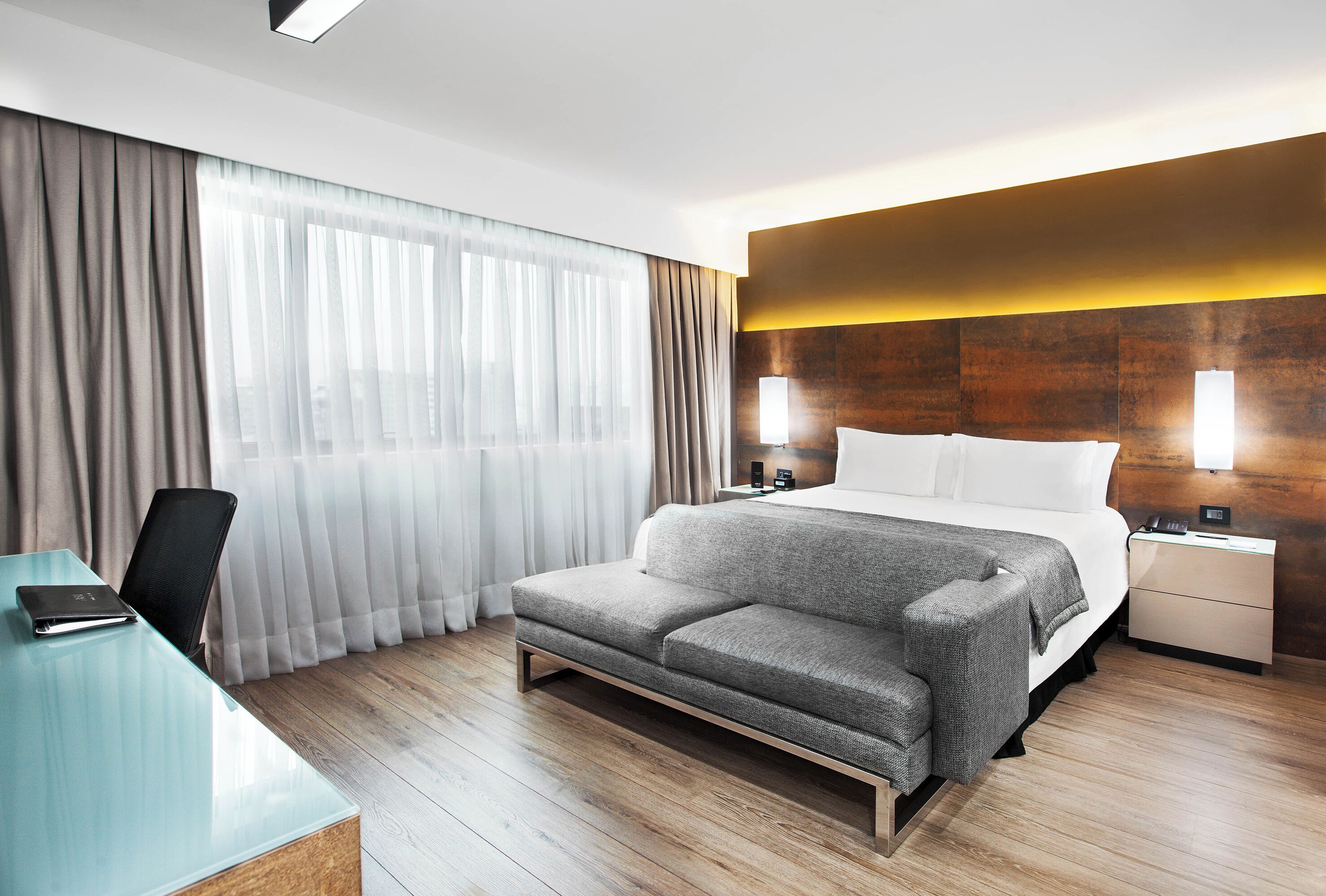 Une chambre d’hôtel moderne, dotée d’un grand lit, d’un bureau et d’une chaise.