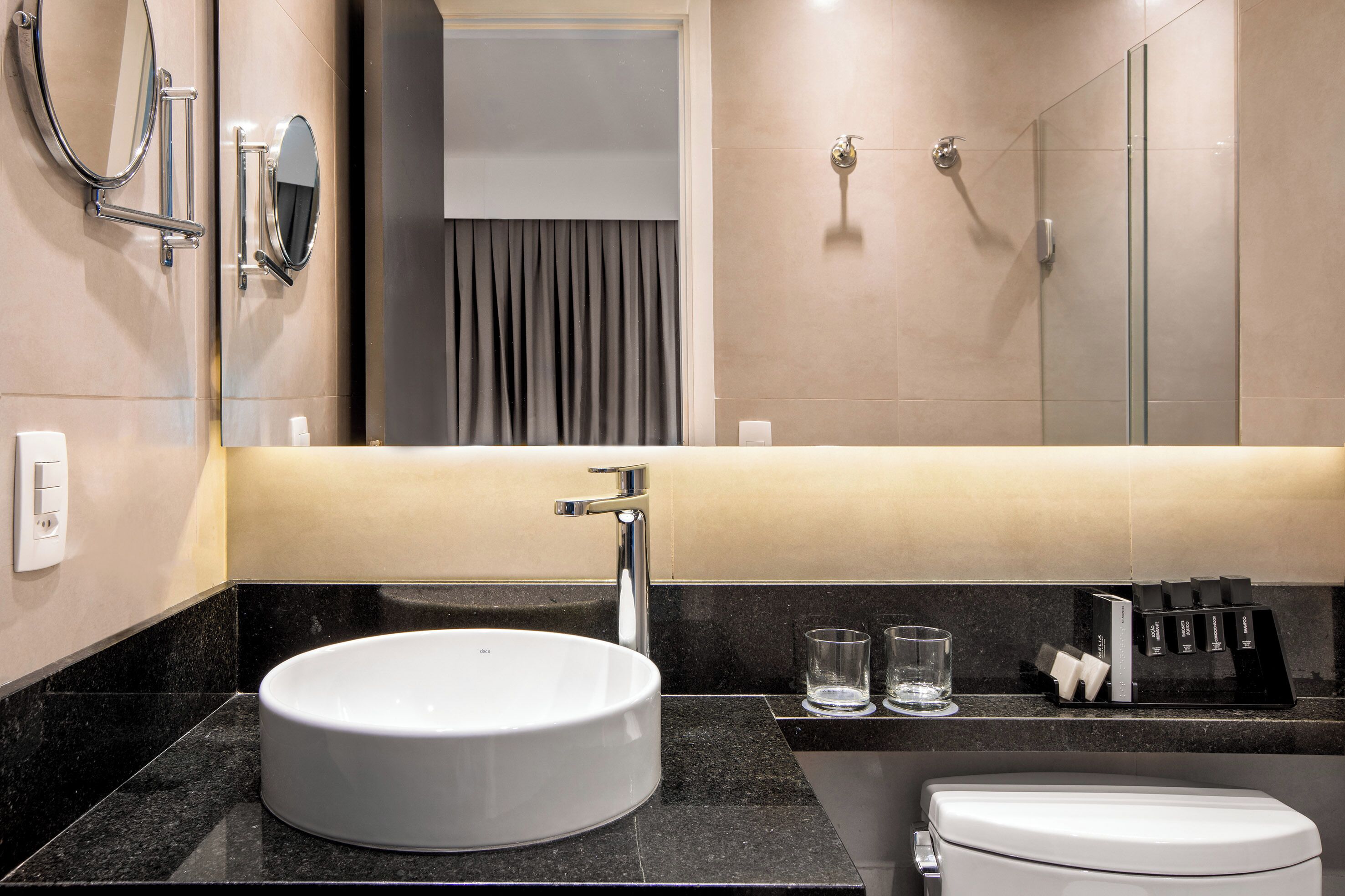 A modern bathroom with a round sink, a mirror, a shower, and a toilet.