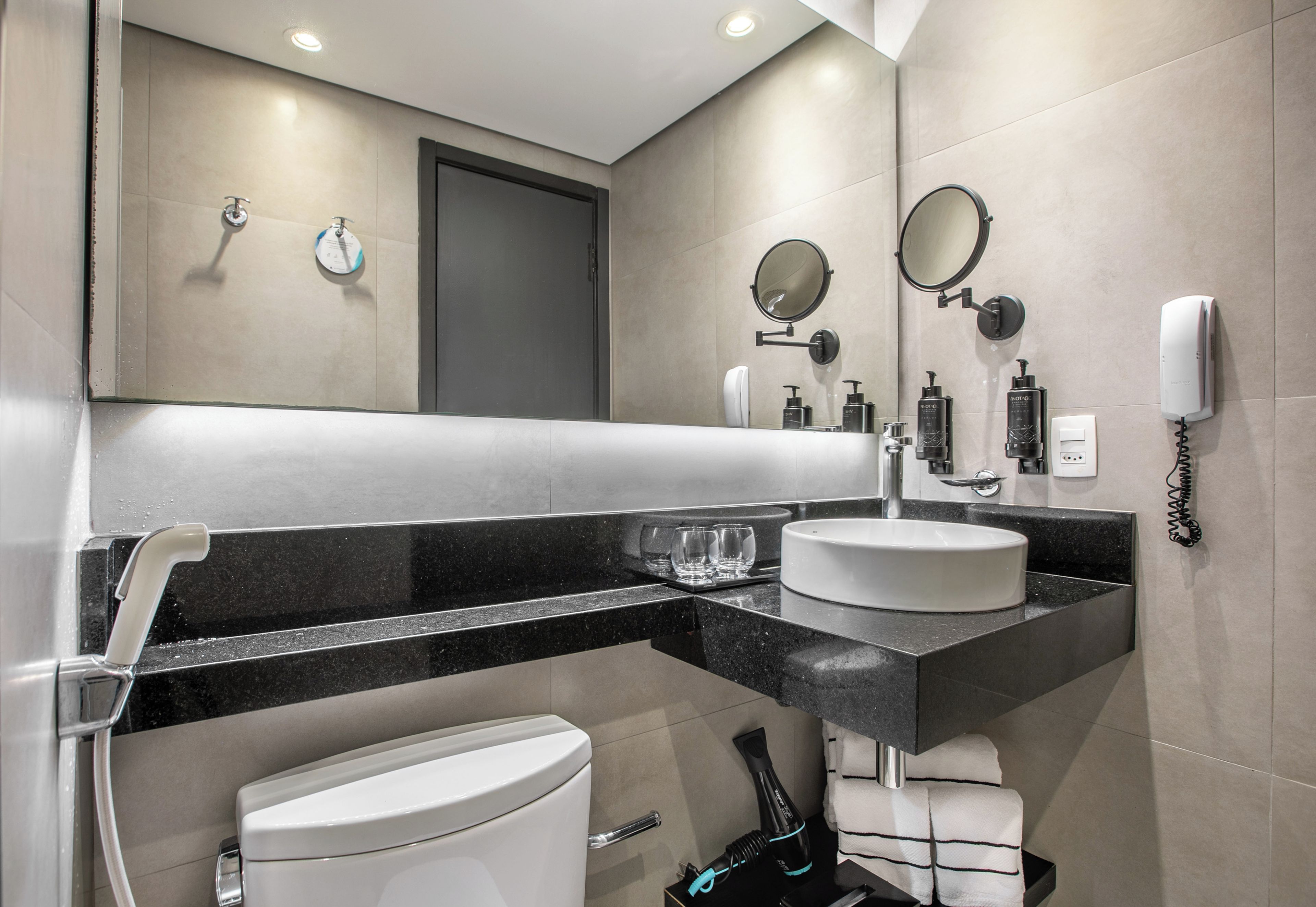 Ein modernes Badezimmer mit Toilette, Waschbecken und Spiegeln.