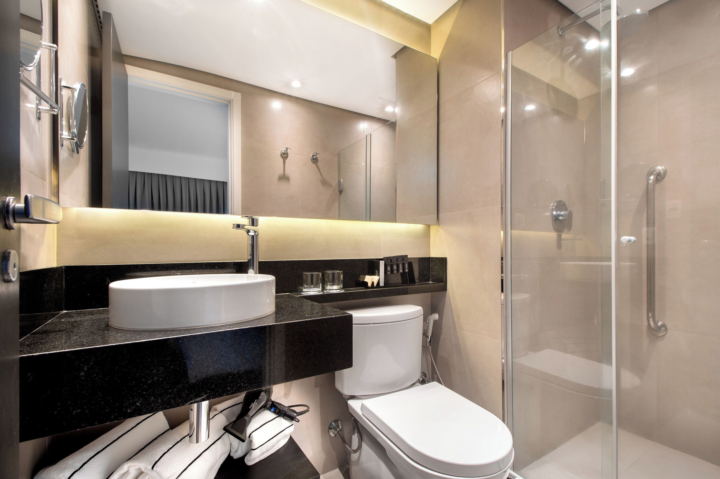 Un baño moderno con lavamanos blanco, inodoro y ducha con mampara de vidrio.
