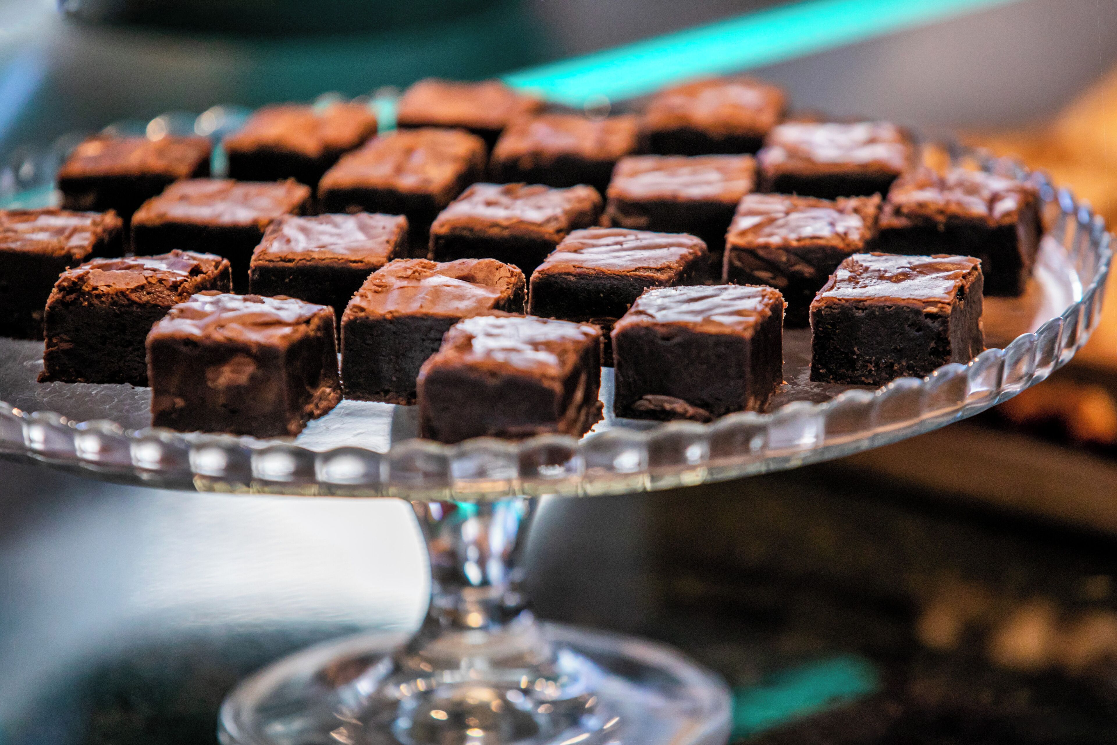 A glass serving dish with several square brownies.