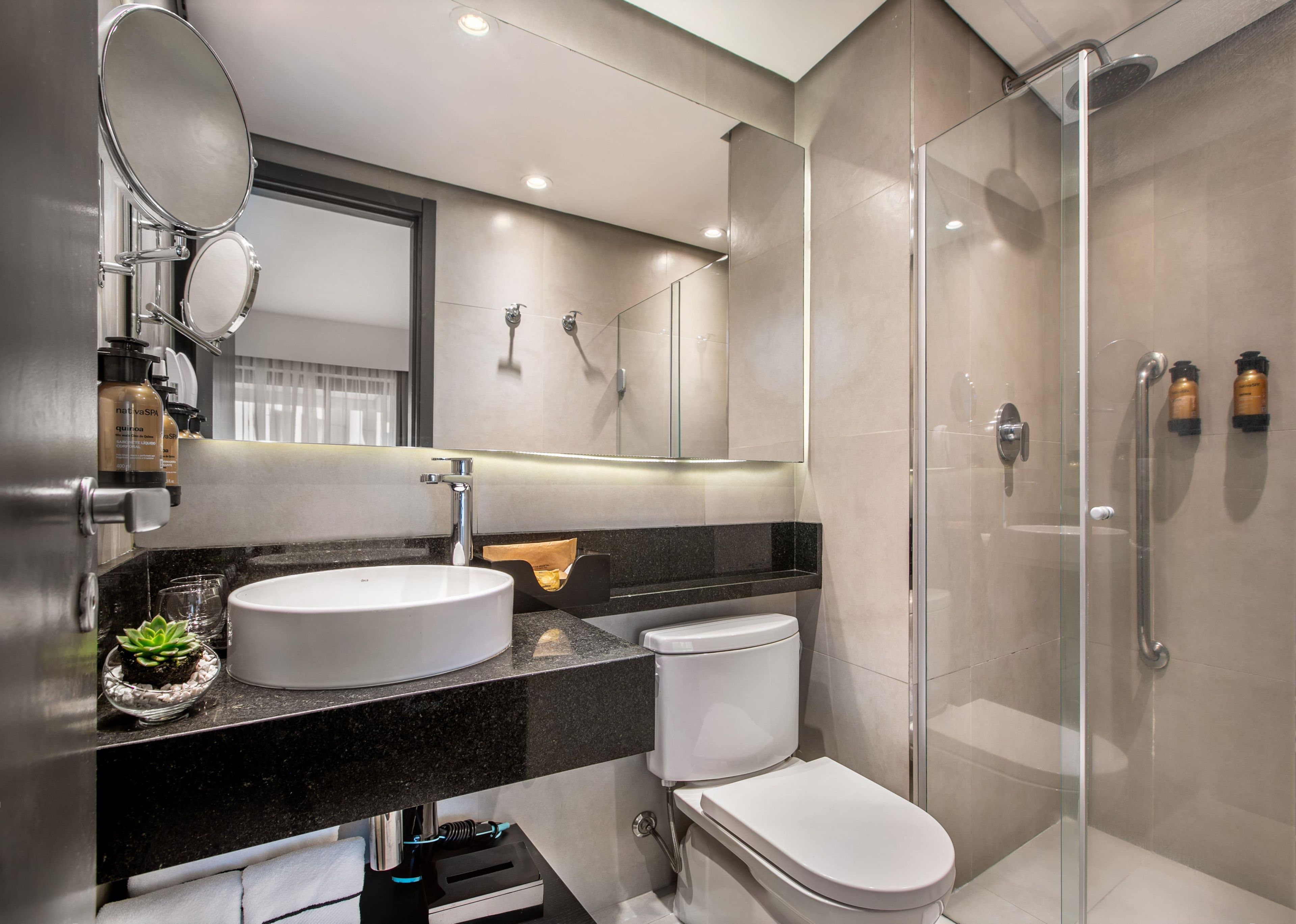Un baño moderno con un lavamanos redondo, inodoro y ducha con mampara de vidrio.