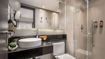 Un baño moderno con un lavamanos redondo, inodoro y ducha con mampara de vidrio.