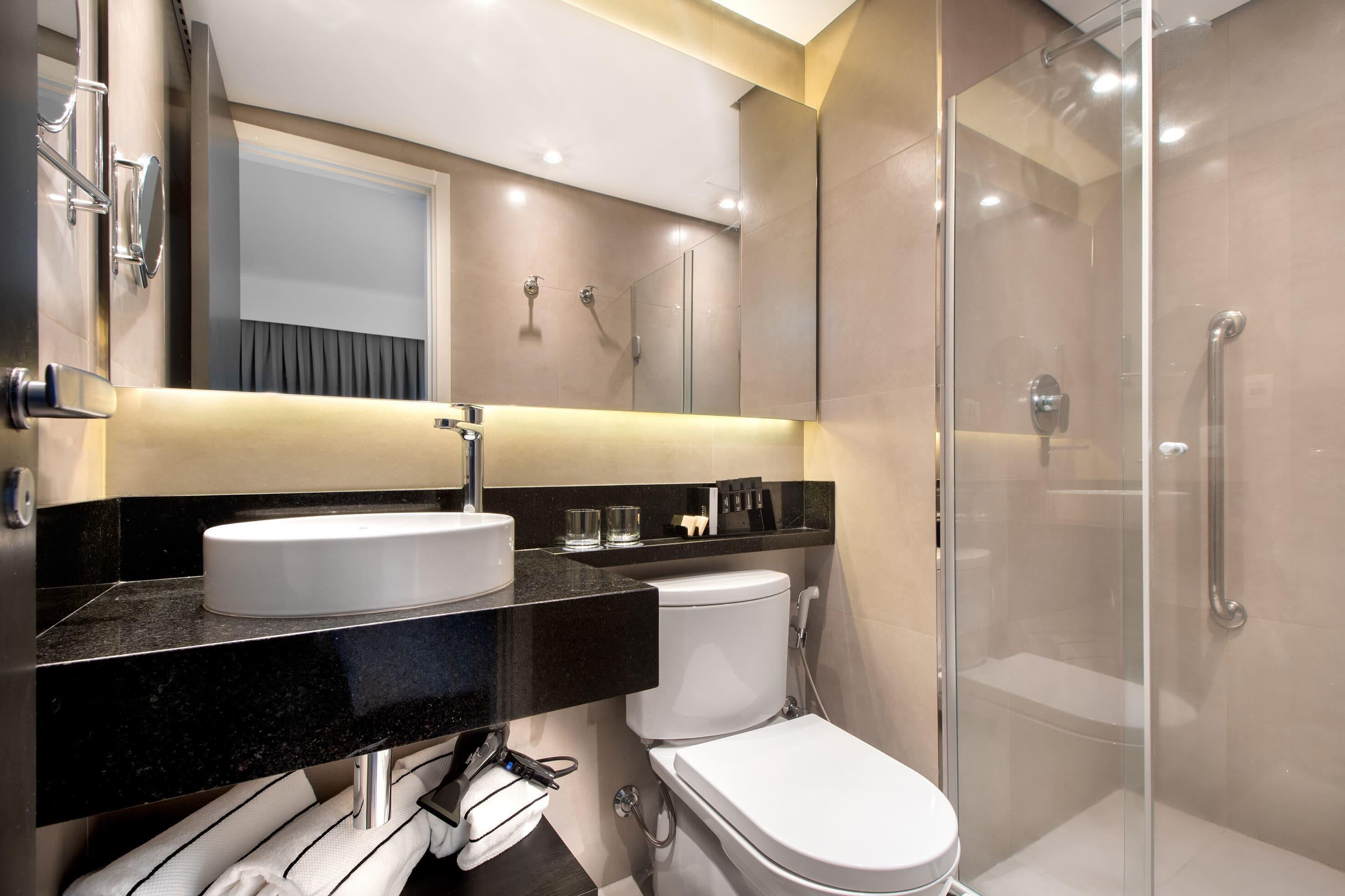 A modern bathroom with a white sink, toilet, and glass-enclosed shower.