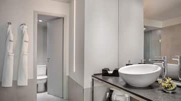 Un baño moderno con un lavamanos grande de color blanco, un espejo y dos toallas colgadas en ganchos.