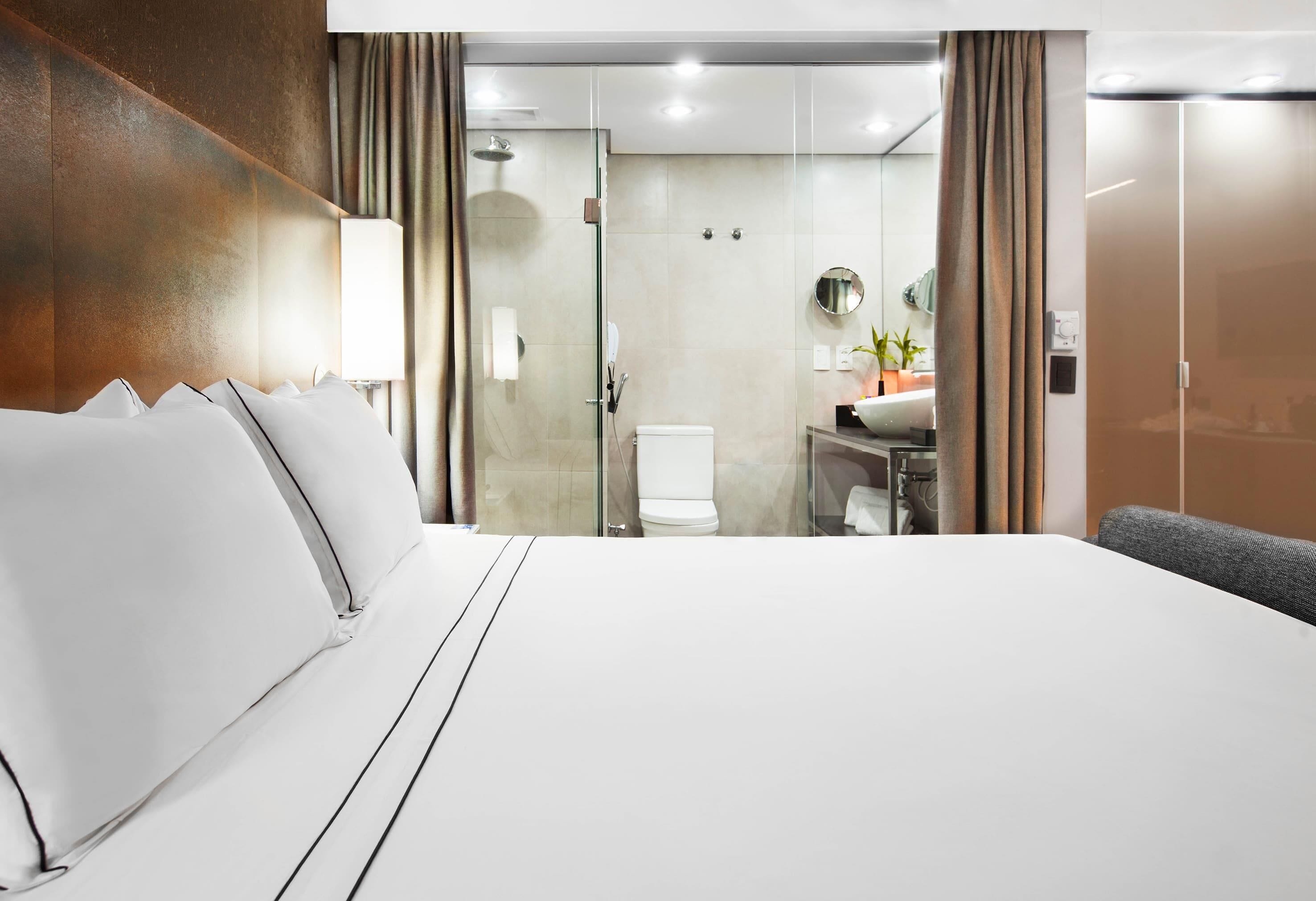 A hotel room with a large bed, a bathroom with a shower, and a sink.