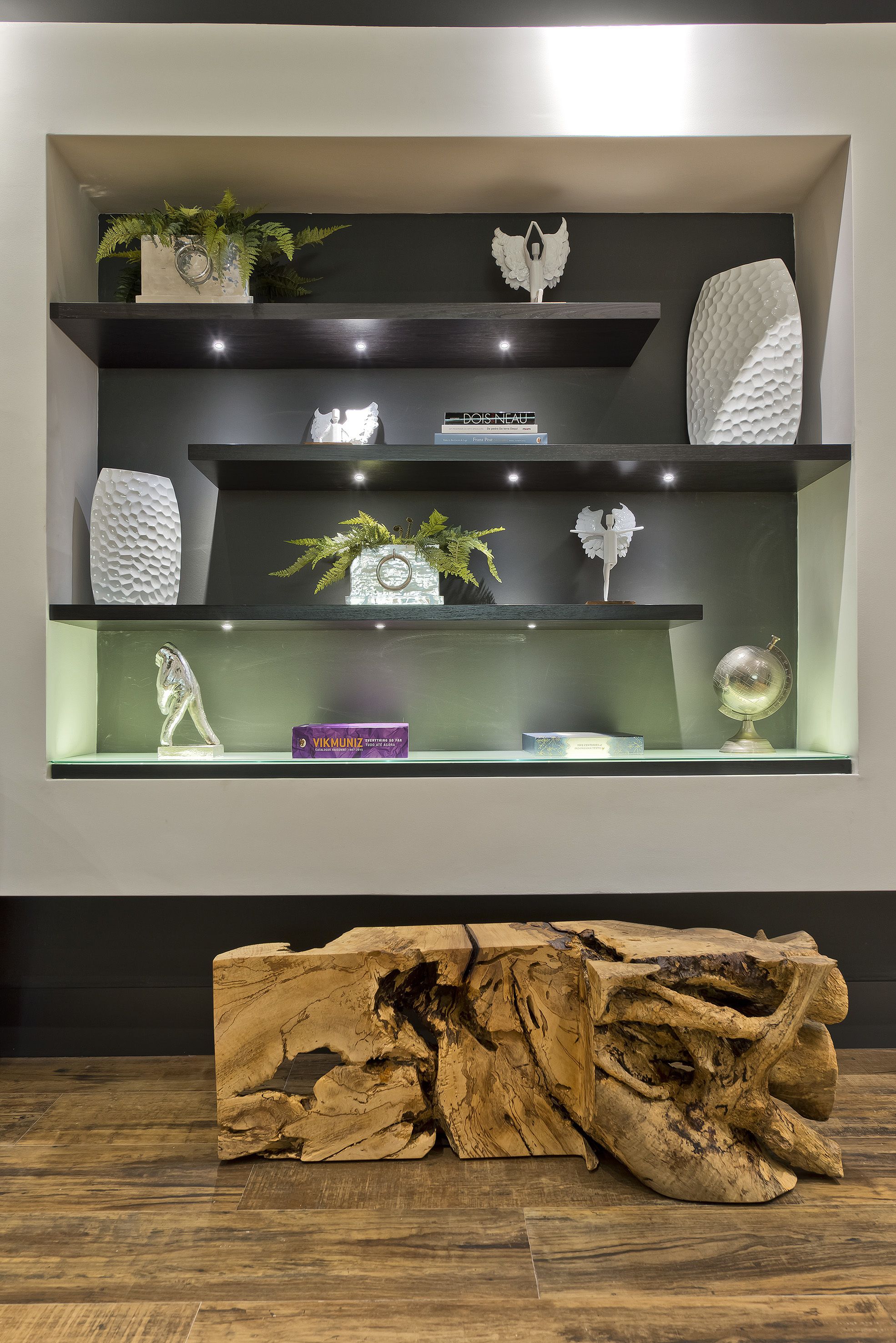 A modern interior with three shelves displaying decorative items and a large wooden sculpture.
