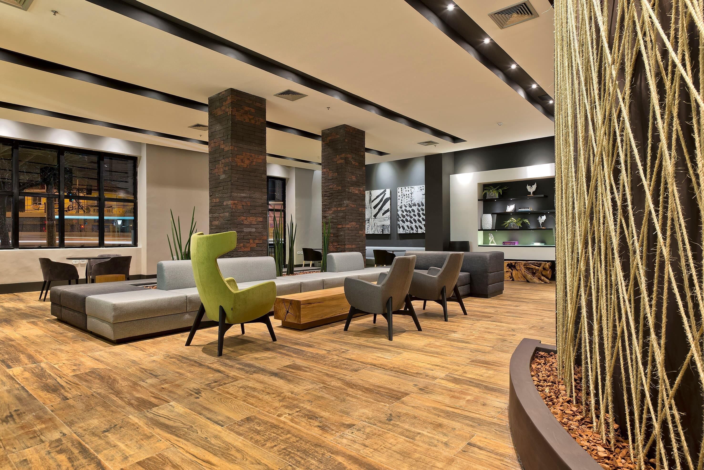 Een moderne lobby met een hoekbank, fauteuils, een houten salontafel en een cactus.