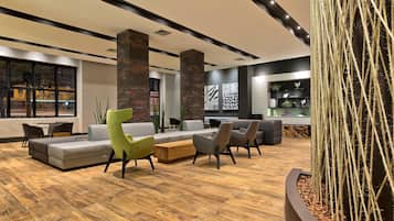 Een moderne lobby met een hoekbank, fauteuils, een houten salontafel en een cactus.