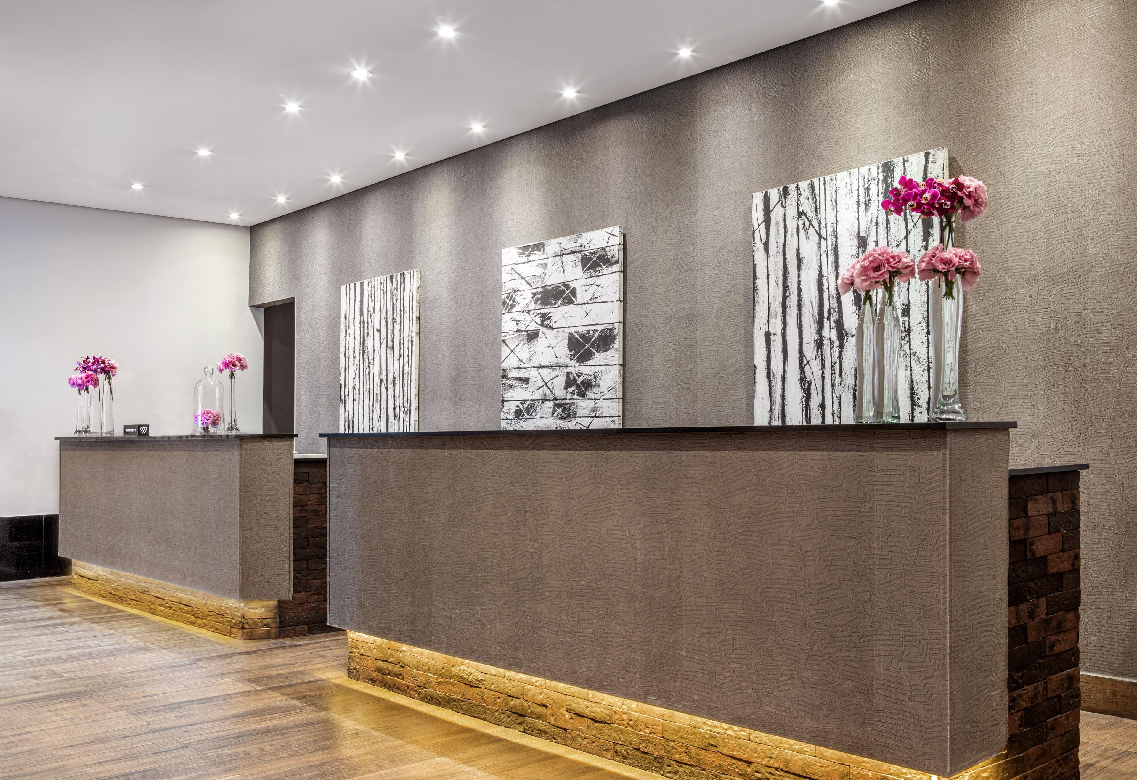 Un espace d’accueil au design moderne, comprenant un comptoir de réception, des œuvres d’art accrochées au mur et un mur décoratif en briques.