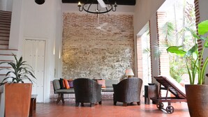 A spacious indoor area with a brick wall, wicker furniture, and potted plants. - Hotel El Candil de los Santos (Cartagena)