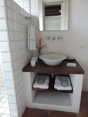 A bathroom with a white sink, a mirror, and two shelves with folded towels. - Hotel El Candil de los Santos (Cartagena)