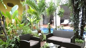 A patio area with wicker furniture, a small table, and various potted plants. - Hotel El Candil de los Santos (Cartagena)