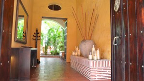 A hallway with a tiled floor, a large vase with candles, and a wooden door. - Hotel El Candil de los Santos (Cartagena)