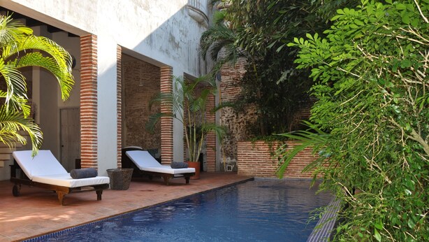 A swimming pool with lounge chairs and potted plants. - Hotel El Candil de los Santos (Cartagena)
