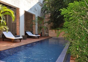 Uma piscina com espreguiçadeiras e plantas em vasos.
