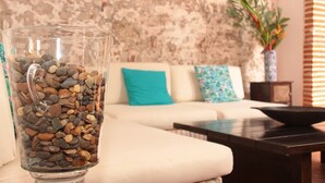 A living room with a white sofa, a glass vase with pebbles, and a decorative plant. - Hotel El Candil de los Santos (Cartagena)