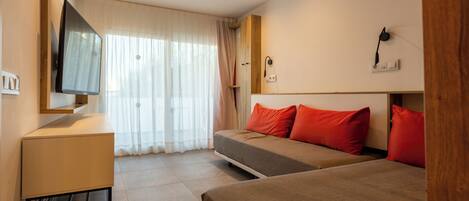 A hotel room with a bed, a desk, a TV, and a window with curtains.