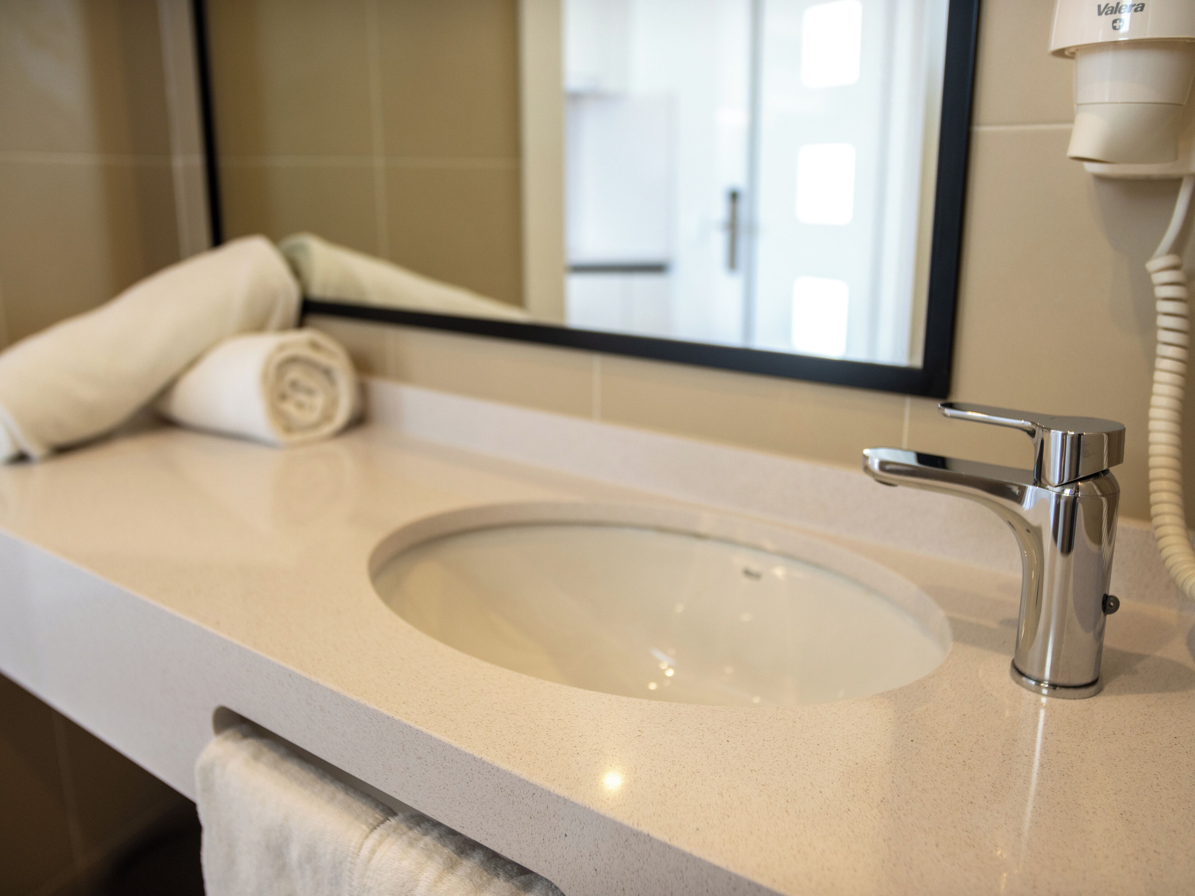 A bathroom with a sink, a towel, and a mirror.