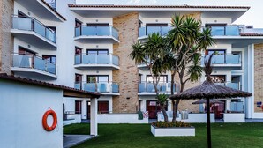 A modern multi-story building with balconies, a grassy courtyard, and a lifebuoy on the wall.