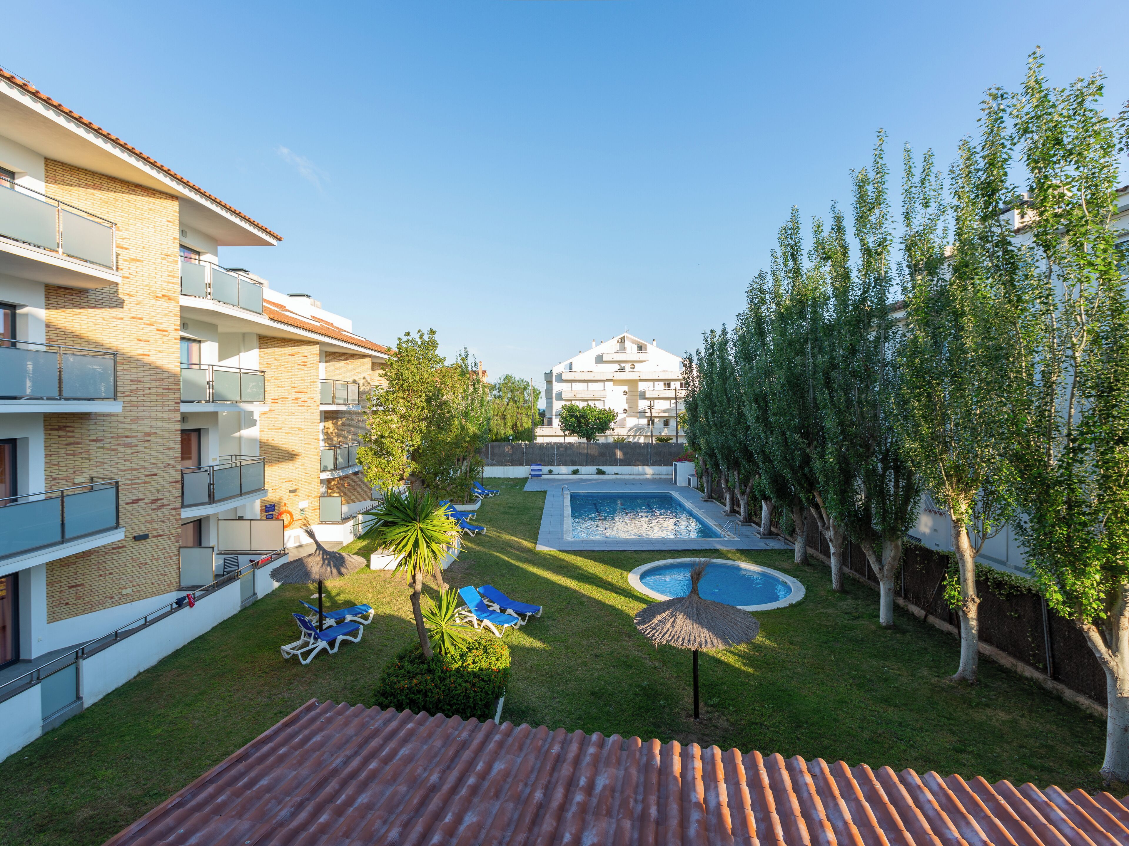 Un cortile con piscina, sedie a sdraio e un piccolo giardino.