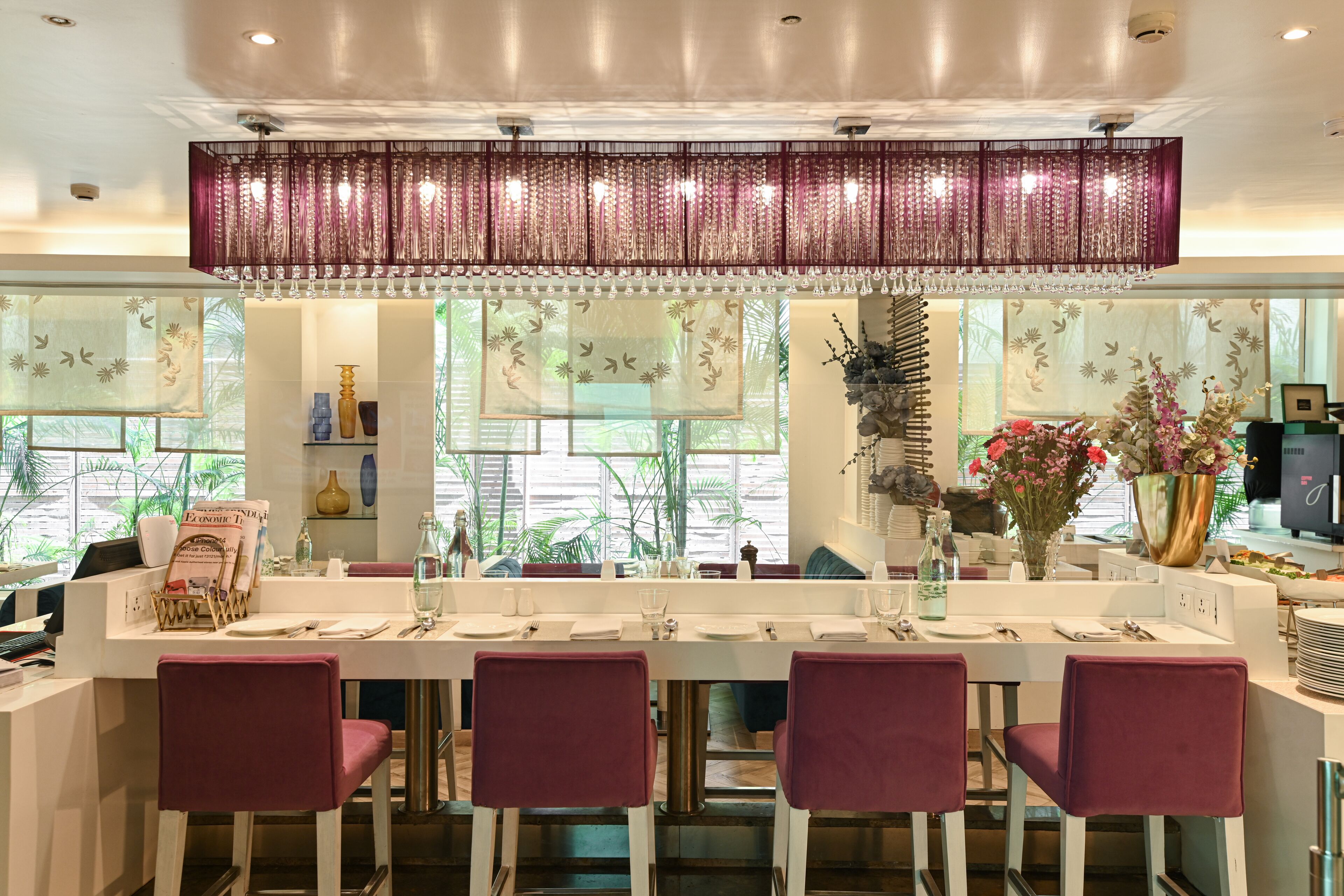 A modern dining area with a long table, four chairs, and a decorative hanging light fixture.