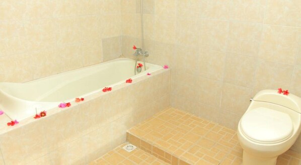Une salle de bain avec une baignoire, des toilettes et un carrelage au sol.