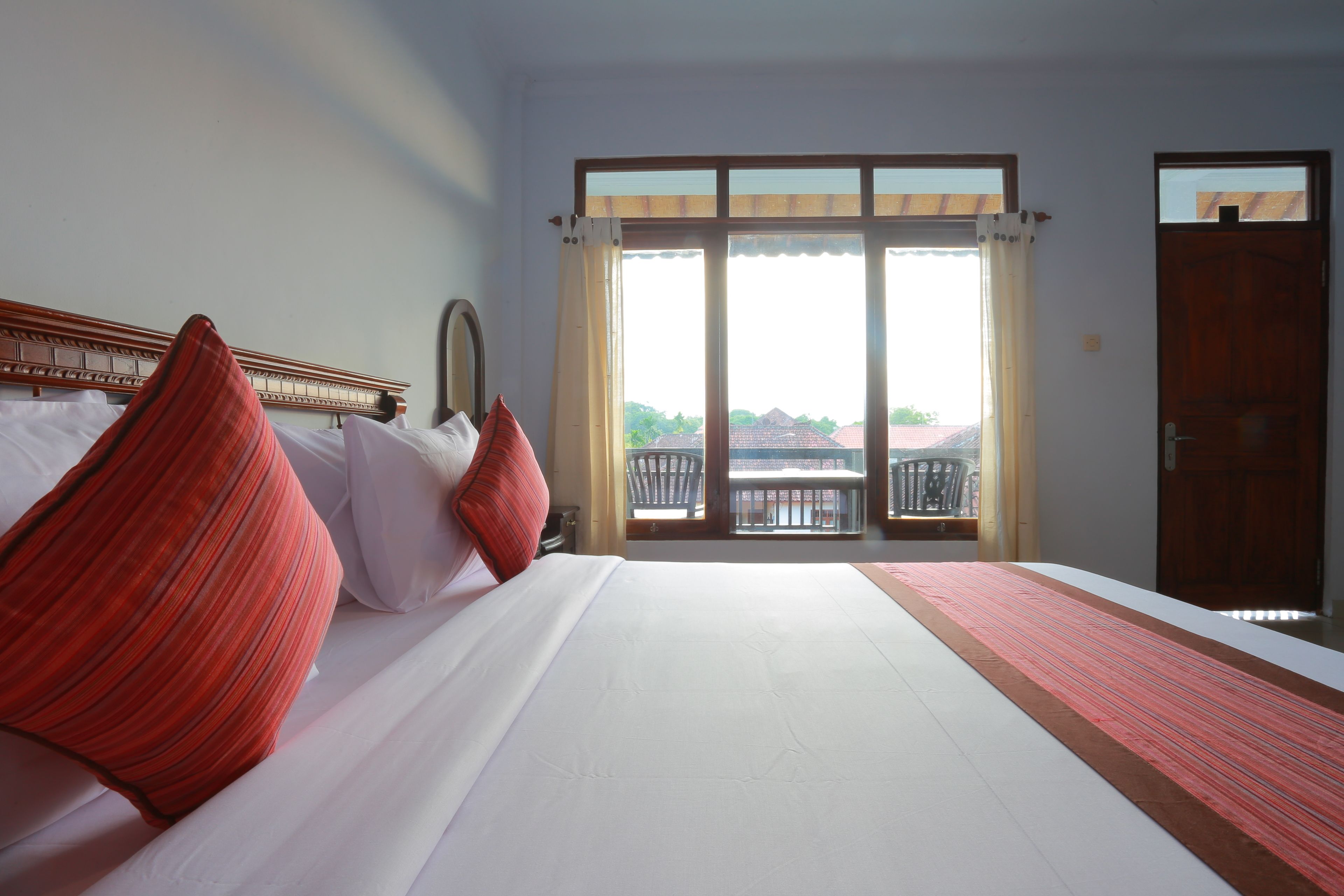 Ein Hotelzimmer mit einem großen Bett, Blick durch eine Schiebetür nach draußen und einem Balkon mit Geländer.