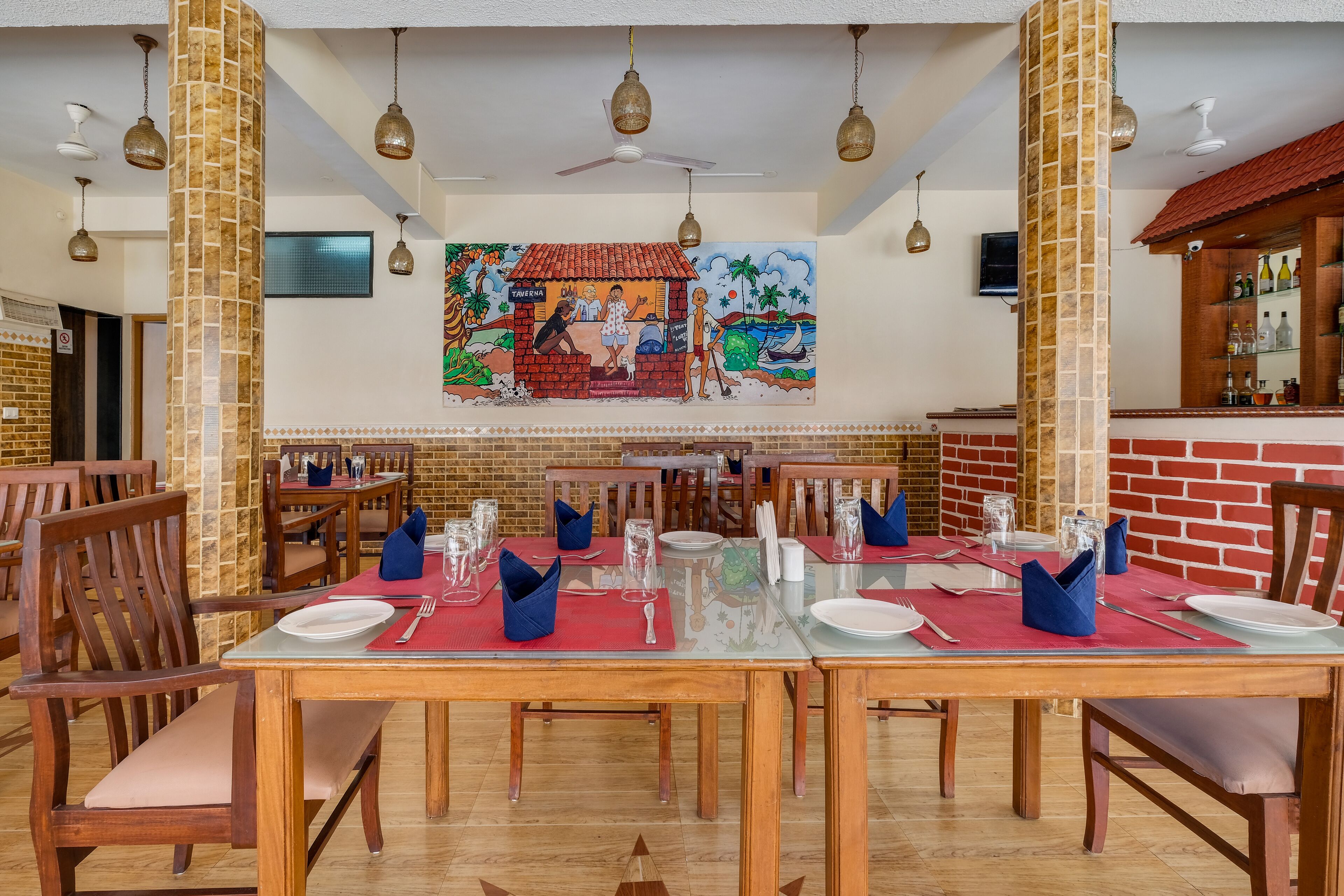 A restaurant with wooden tables and chairs, a mural on the wall, and a bar area.
