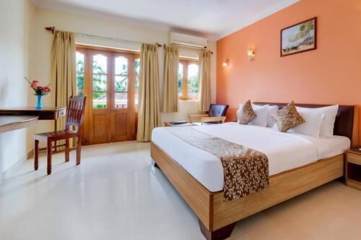 Une chambre d’hôtel avec un lit, un bureau, une chaise et une fenêtre avec des rideaux.